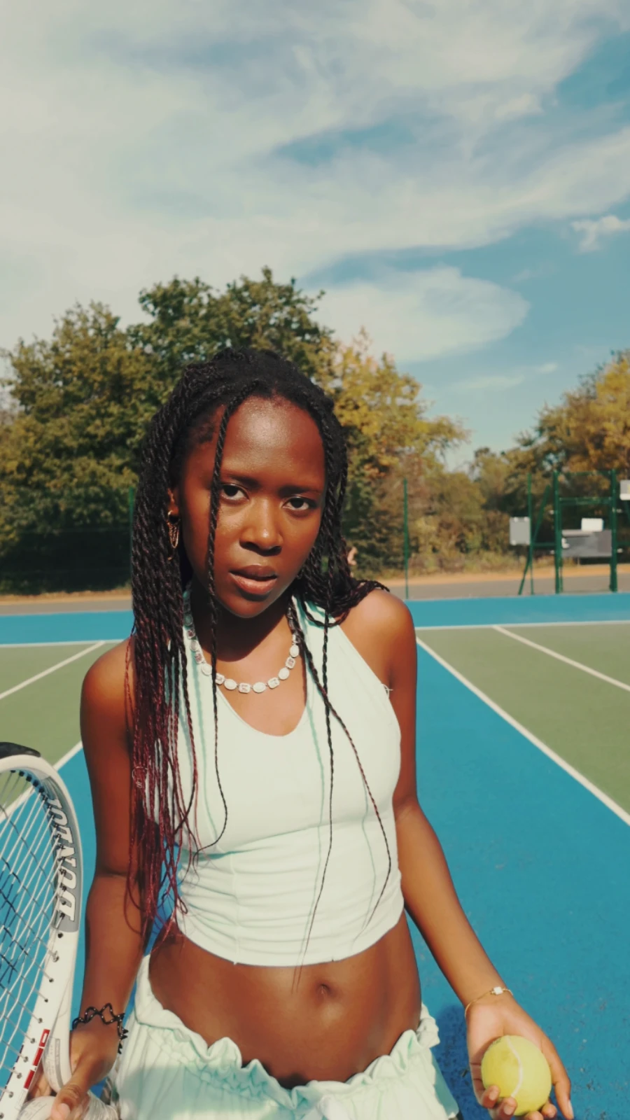Kah'Nya holding a tennis ball and a racket, looking straight at the camera