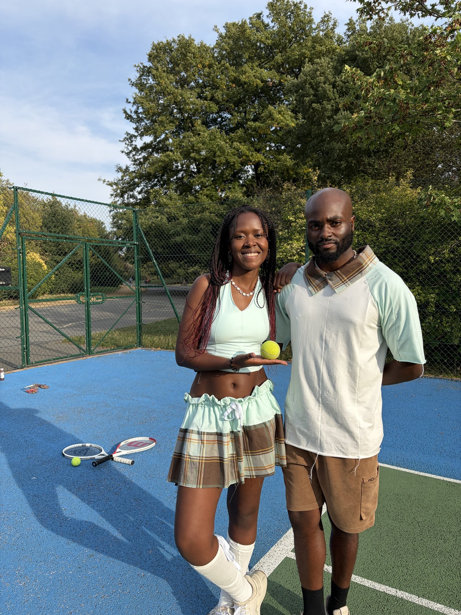 obi and Kah'Nya smiling on court, holding a tennis ball and racket